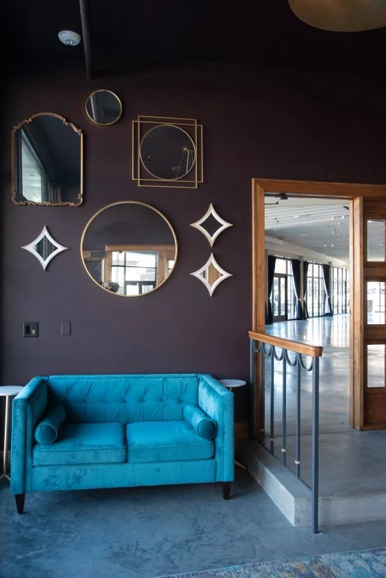 Plum wall of gold mirrors with a teal settee