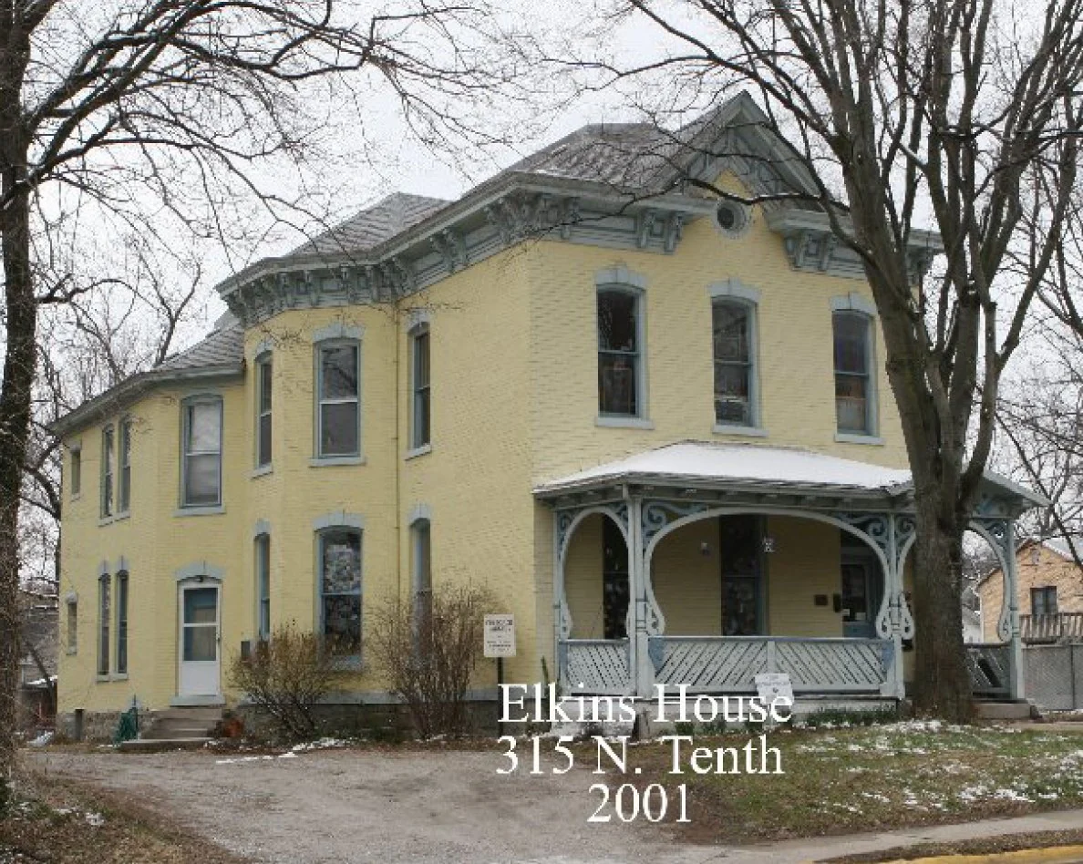 The Elkins House in 2001, painted yellow with blue trim and a curving front porch